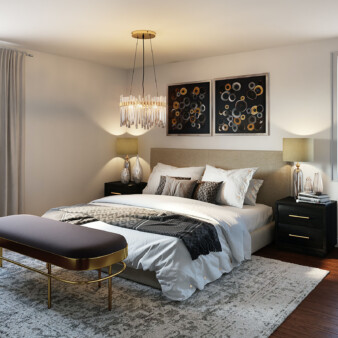 Modern bedroom decorated with earth and grey tones. Bed has a base board in a dark sand color that matches lamps on the sides of the black nigh tables. Two pieces of abstract art with black background adorn the wall behind the bed.