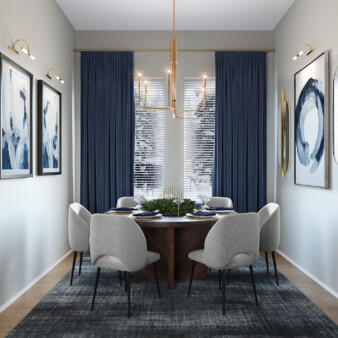 Small elongated dining room area decorated in off-white, greys and blues. A round dining table in dark wood is surrounded by six off-white chairs of simple design. Walls have abstract art pieces in white and blue, and various accents, from a hanging lamp to wall sconces, are in gold.